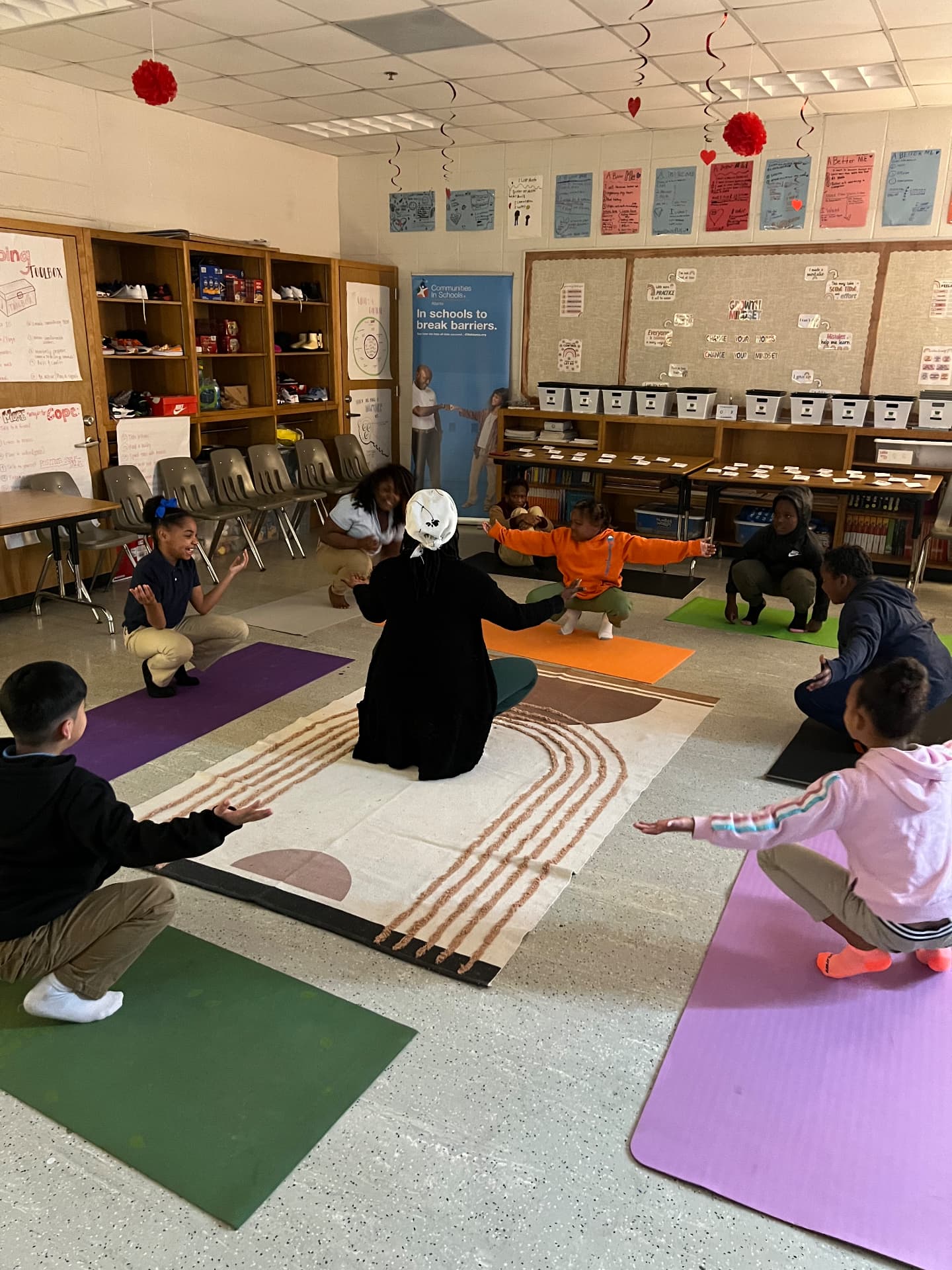 A facilitator leading a movement circle on mats in a classroom